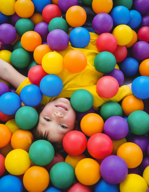 Niño jugando en una piscina de bolas de un parque infantil