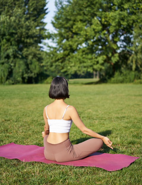 Mujer haciendo yoga en medio de una pradera verde