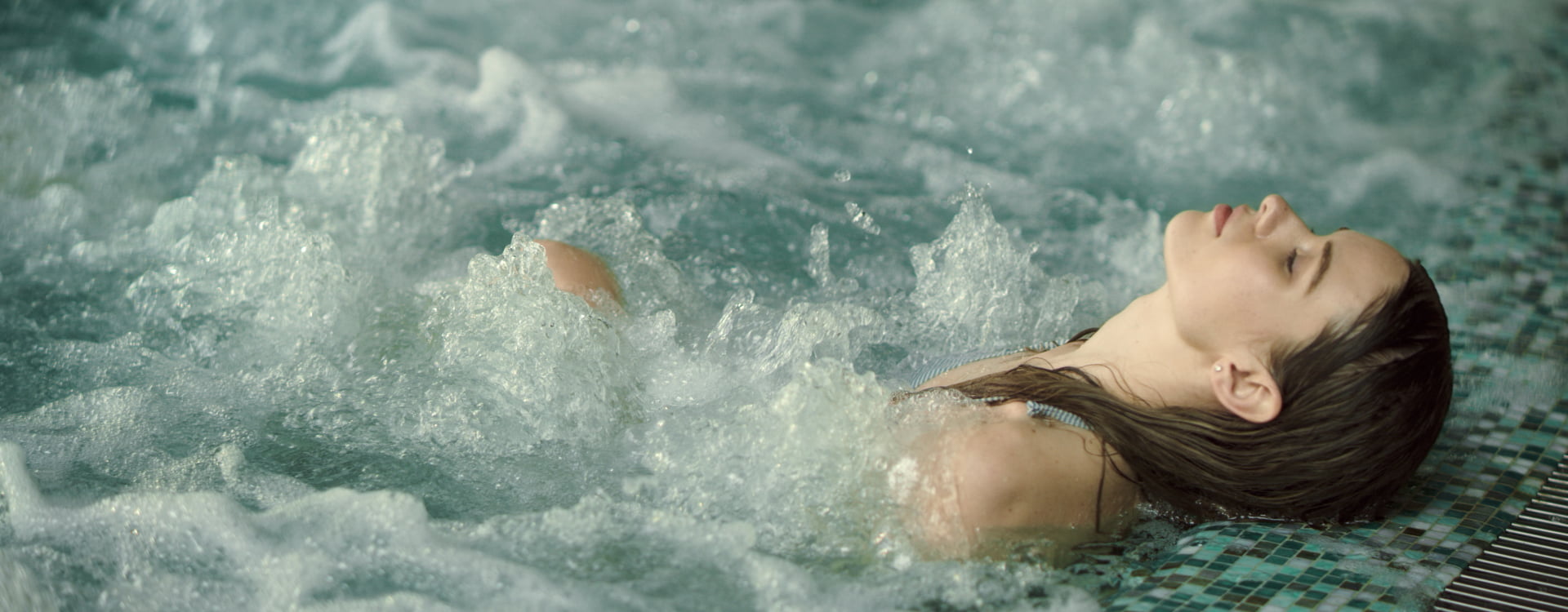 Mujer tumbada relájandose en las piscina del spa