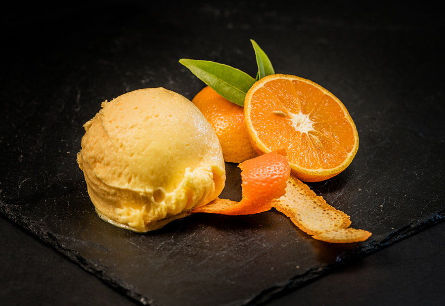 Plato de postre con helado y rodajas de naranja