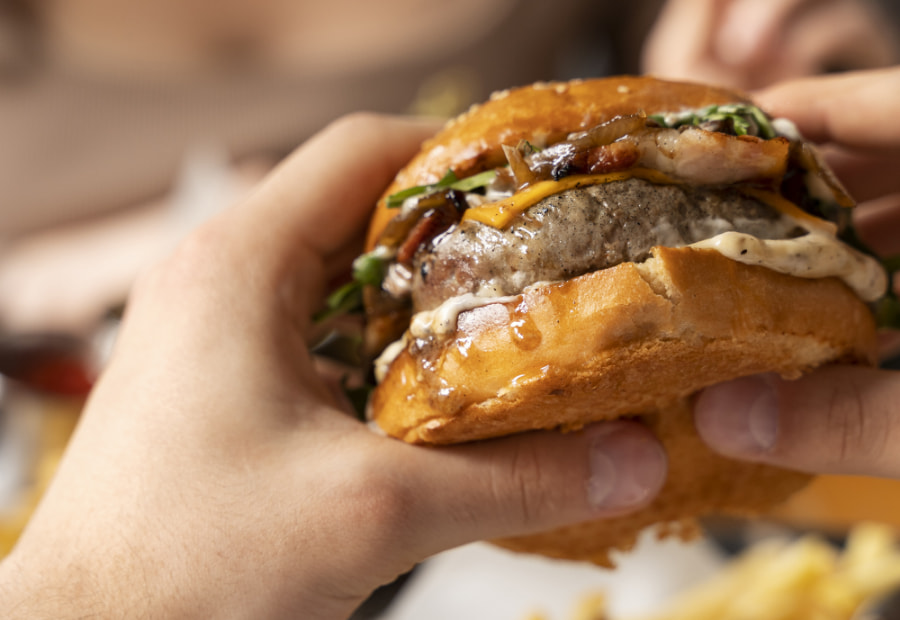 Persona cogiendo una hamburguesa con queso con las dos manos