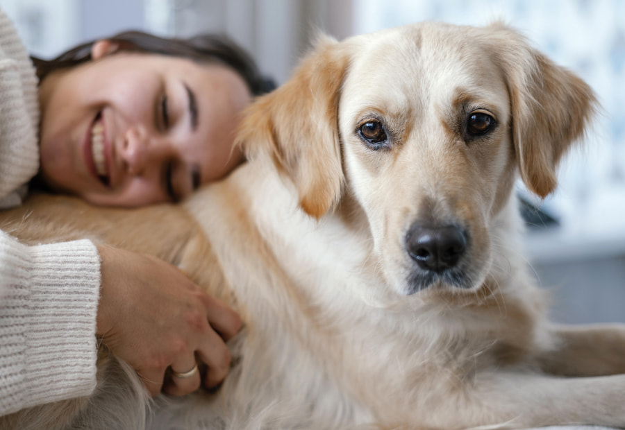 Woman lying smiling and cuddling her dog 