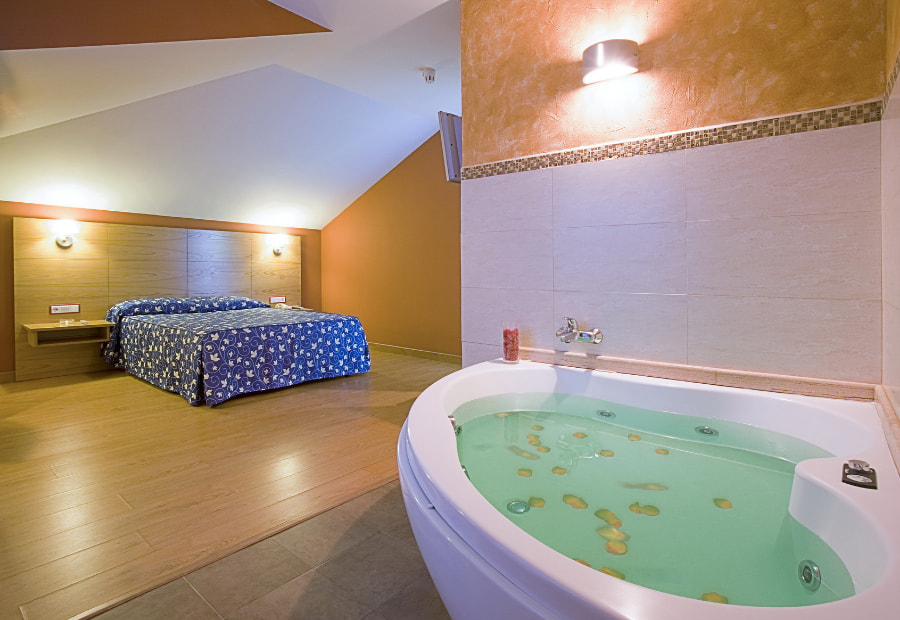 Picture of the room with double bed, television and whirlpool bathtub.