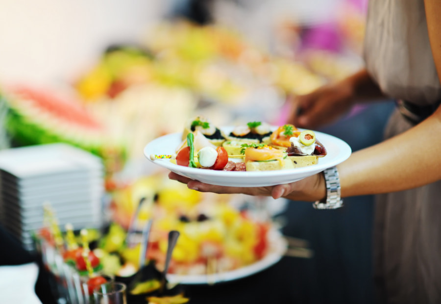 Person holding a plate of food at an open buffet